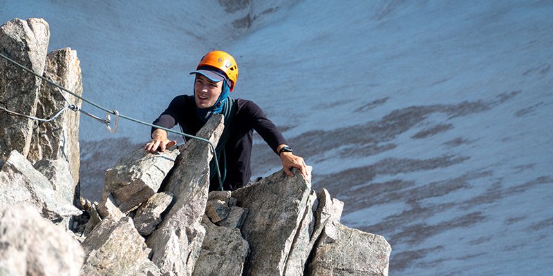 Deelnemer alpiene C2 cursus klimt over een rotspartij 