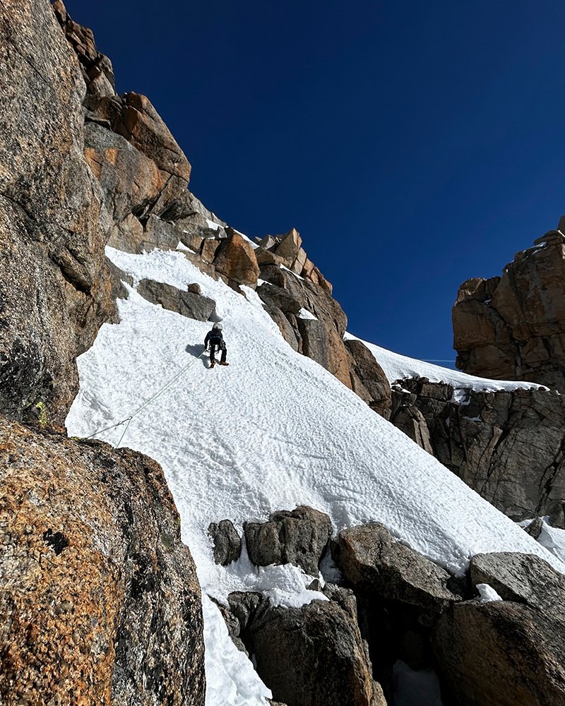 Man klimt sneeuwwand op, boven op een berg