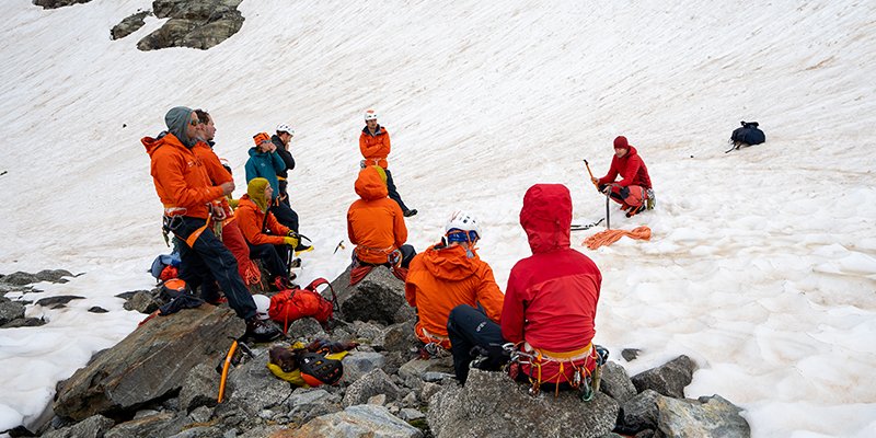 Een groep alpinisten krijgen les over hoe ze met een ijspickel kunnen zekeren