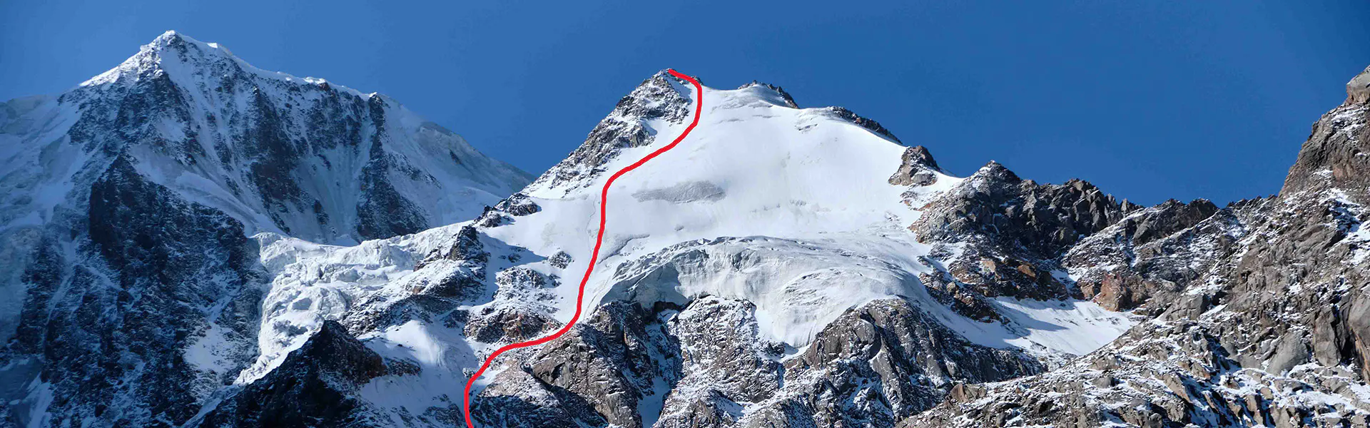 Drie bergbeklimmers met helmen en jassen op glimlachen naar de camera terwijl ze op een zonnige berg staan.